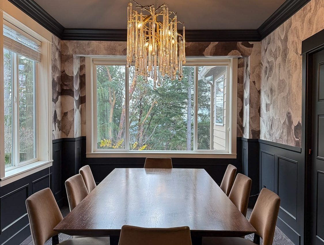 Modern elegant dining room with dark wood table, plush chairs, and stylish chandelier.