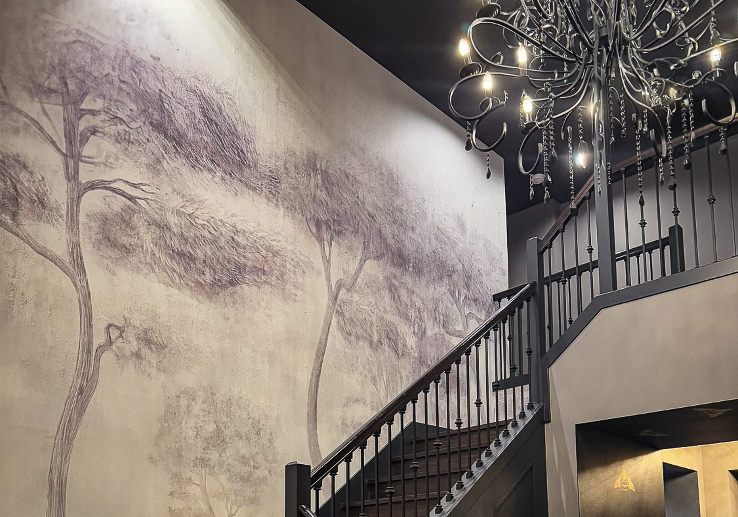 Elegant staircase with mural art and chandelier in contemporary interior design.