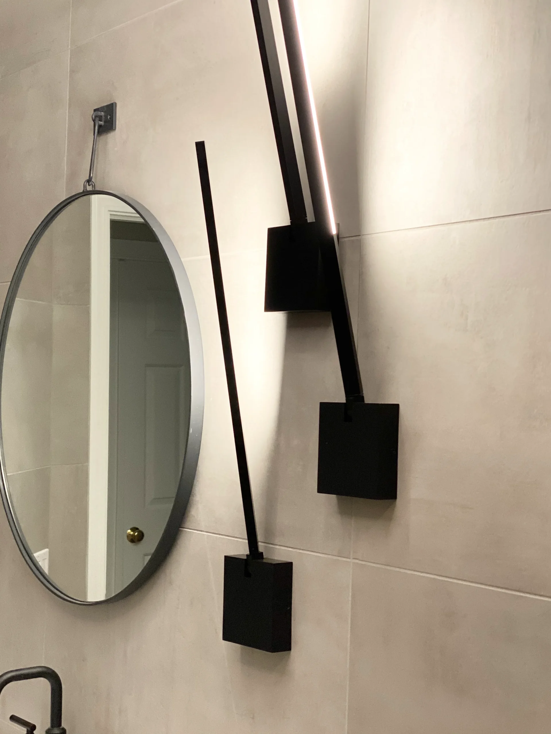Modern bathroom with round mirror and geometric lighting — Ariana Designs