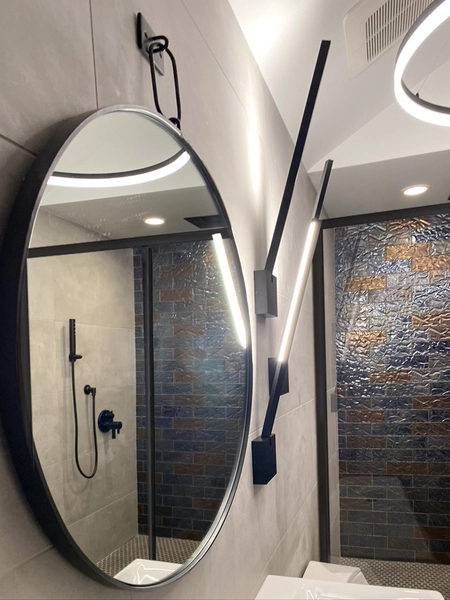 Contemporary bathroom with warm lighting and textured wall tile — Ariana Designs