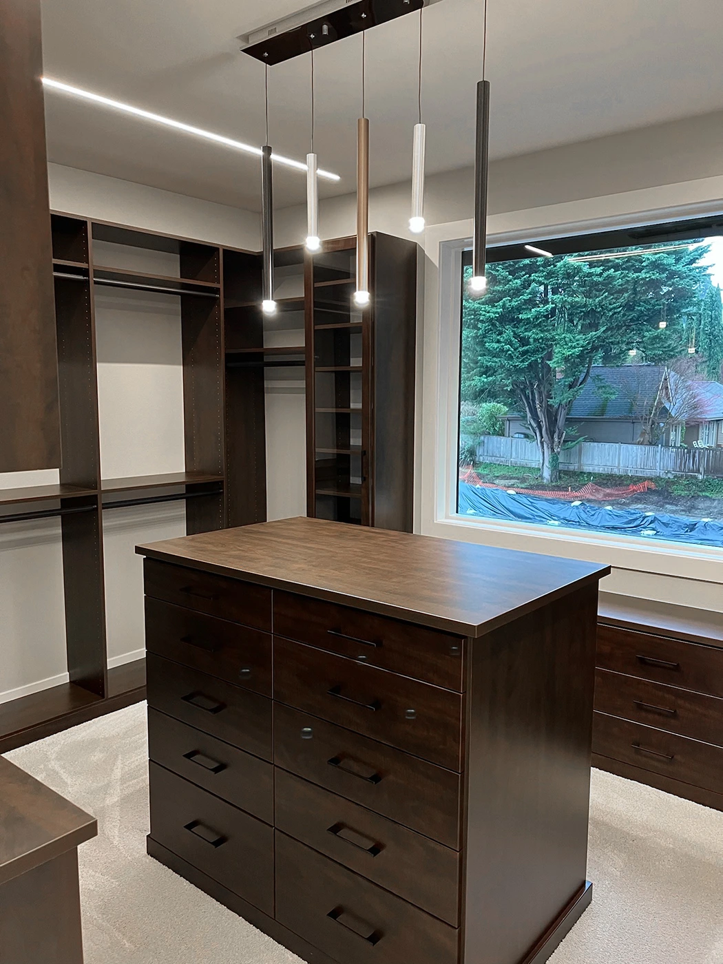 Stylish modern dressing area with dark wood cabinetry, elegant lighting, and organized open shelving.