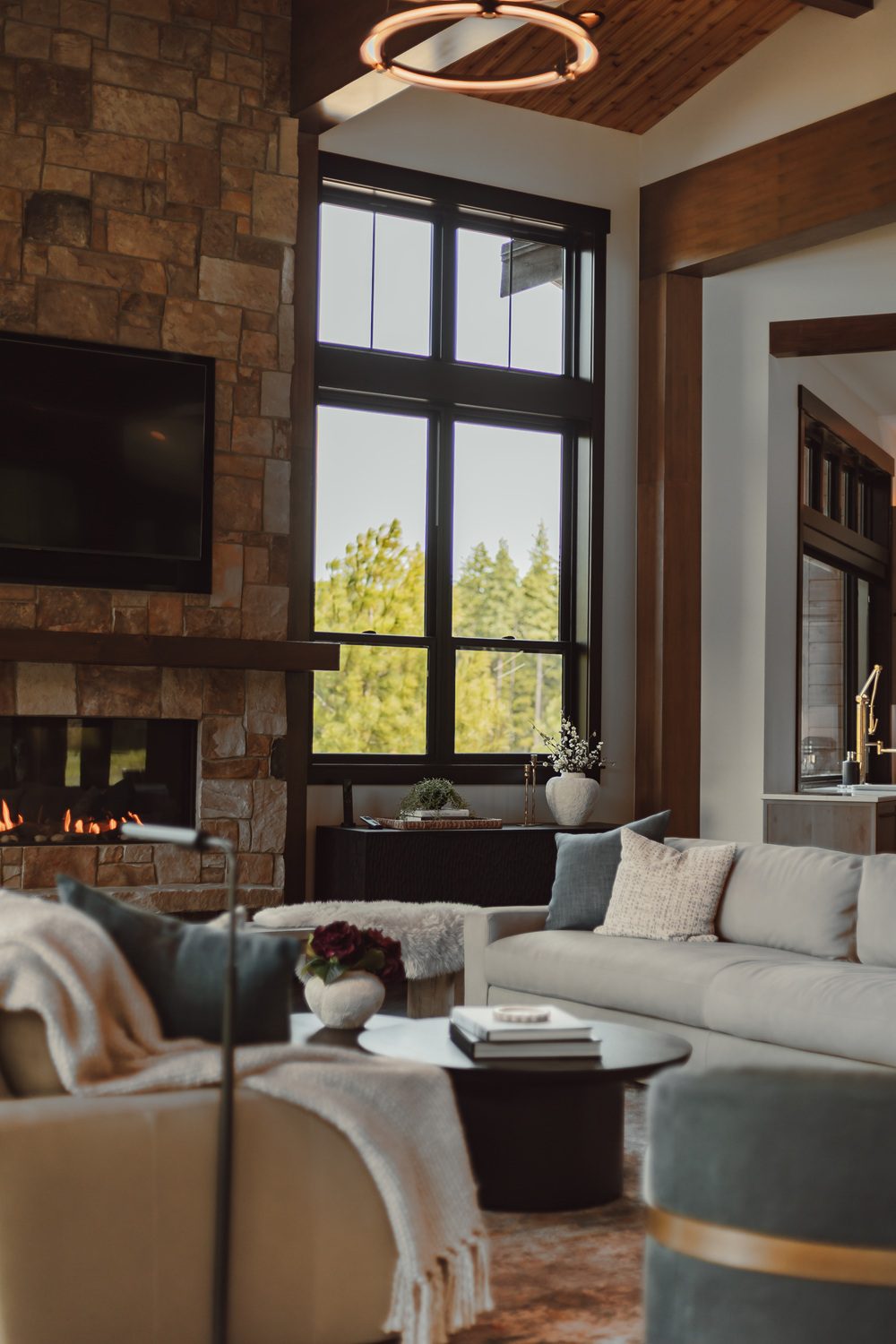Comfortable lounge beside the stone fireplace in a vaulted mountain family room — Ariana Designs & Interiors