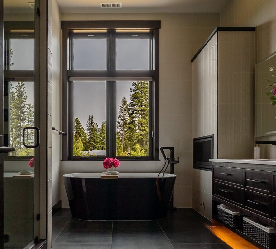 Modern walk-in shower featuring black fixtures, light gray wall tiles, and a built-in bench illuminated by soft LED accent lighting.