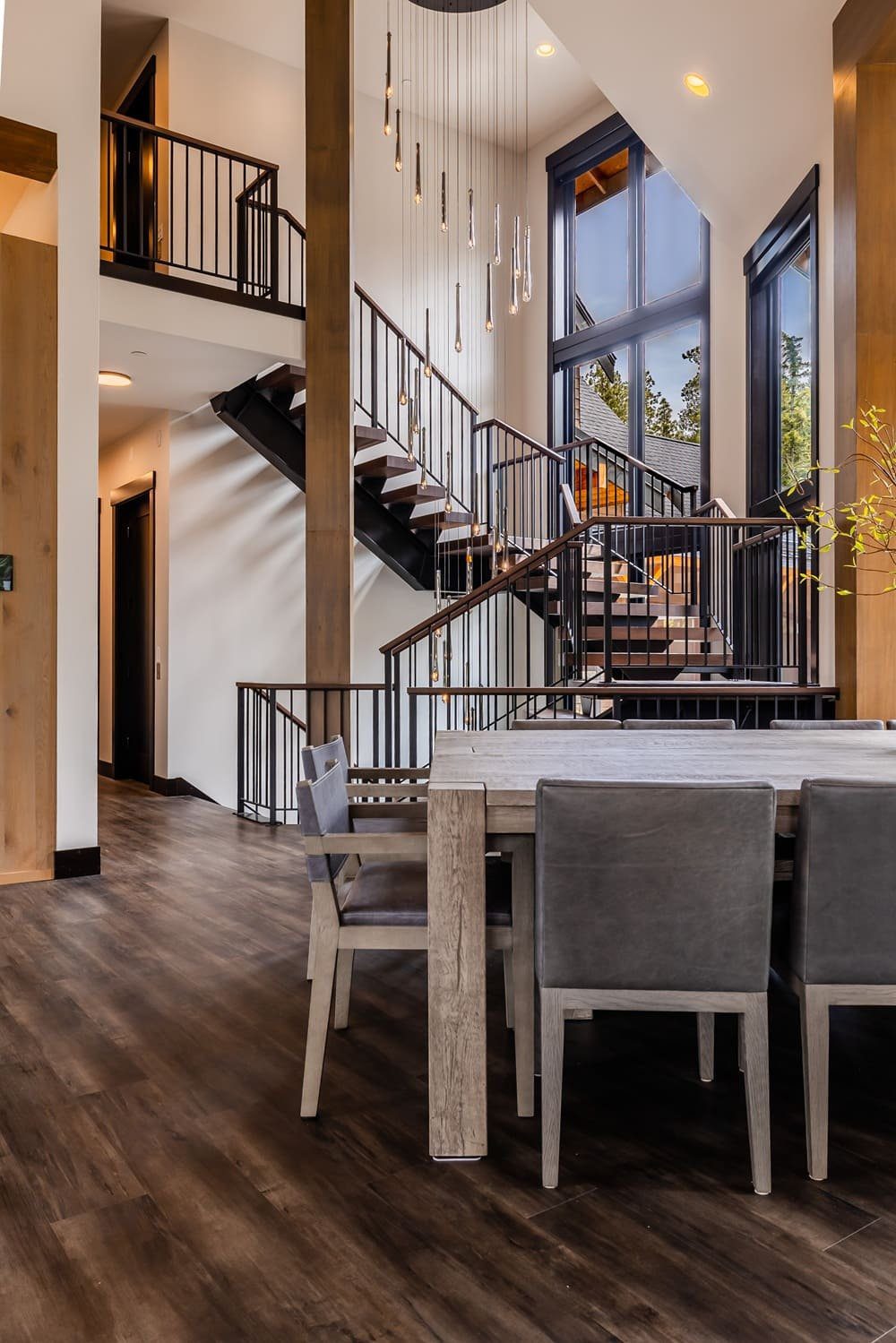Wide stairwell view with pendant cascade and forest beyond — Suncadia Retreat